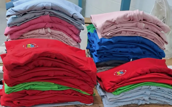 Stacks of colourful custom hoodies prepared by custom hoodie suppliers for school leavers.