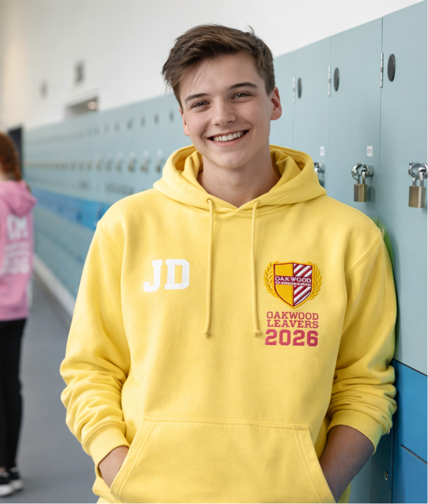 Person wearing a yellow hoodie with 'JD' and 'Dawson Leavers 2026' text, standing in a school corridor.